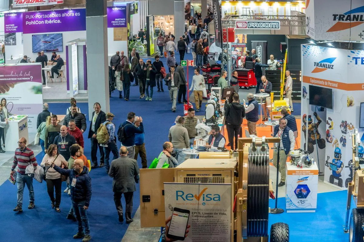 Pasillo de un pabellón de GENERA con stands de material eléctrico y visitantes profesionales